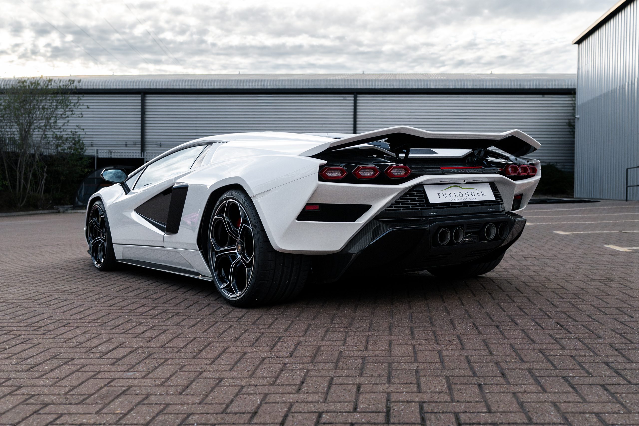 Rear three-quarter view of the white Countach LPI 800-4 showing its fixed rear wing, six hexagonal tail lights, carbon diffuser and four exhaust tips.